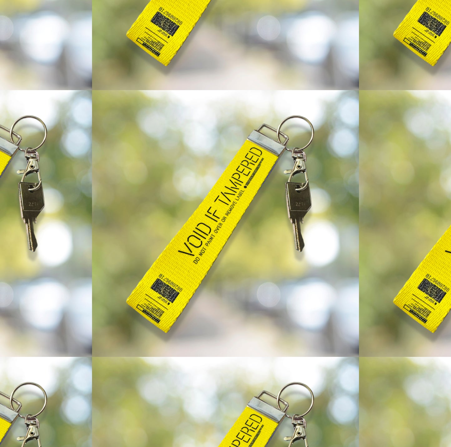May include: A yellow security strap with a metal ring. The strap has black text that reads 'VOID IF TAMPERED' and 'DO NOT PAINT OVER OR REMOVE LABEL'. A barcode and other text are printed on the strap. The strap is angled against a background with a blur decorations.