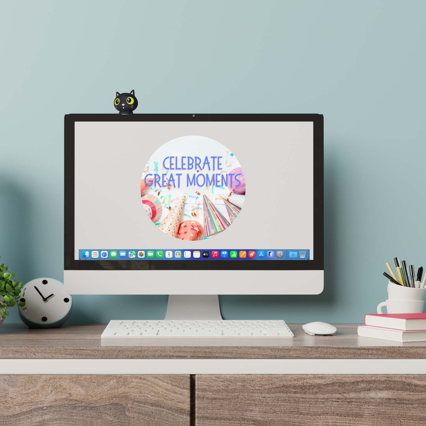 Computer monitor on a desk with a 'Celebrate Great Moments' screen, surrounded by office supplies. Black cat figurine with yellow eyes on a computer monitor